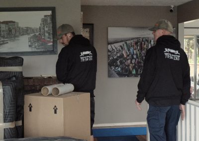 Two members of uptown moving packing boxes for a residential move